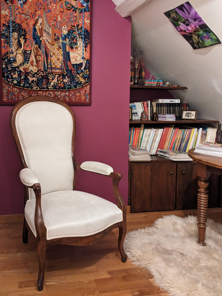 Fauteuil Voltaire retapissé avec un tissu blanc cassé et finition double passepoil assorti